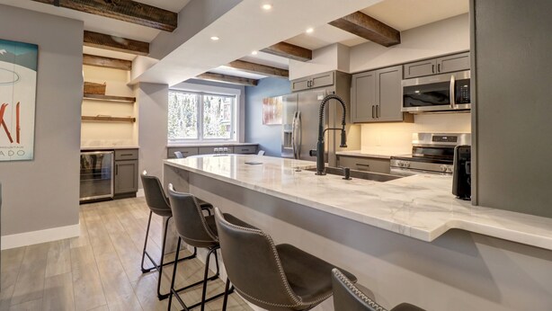 Una cocina moderna con una isla grande, taburetes de bar y electrodomésticos integrados.