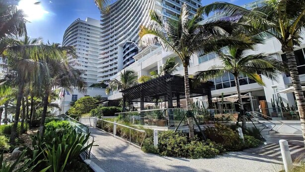 A modern hotel with a curved facade, surrounded by palm trees and a well-maintained garden. - 1201 W S 1 Bedroom Condo by RedAwning (Fort Lauderdale)