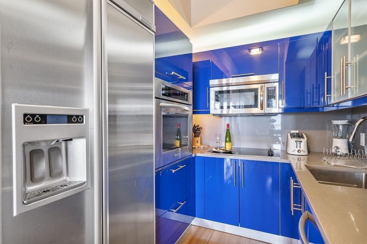 Una cocina moderna con armarios azules, electrodomésticos de acero inoxidable y un dispensador de agua empotrado.