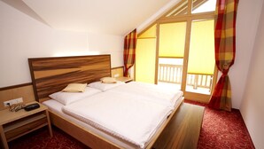 A neatly made bed with a wooden headboard, a bedside table with a lamp, and a bench. - Residenz Cristallo (Reit im Winkl)
