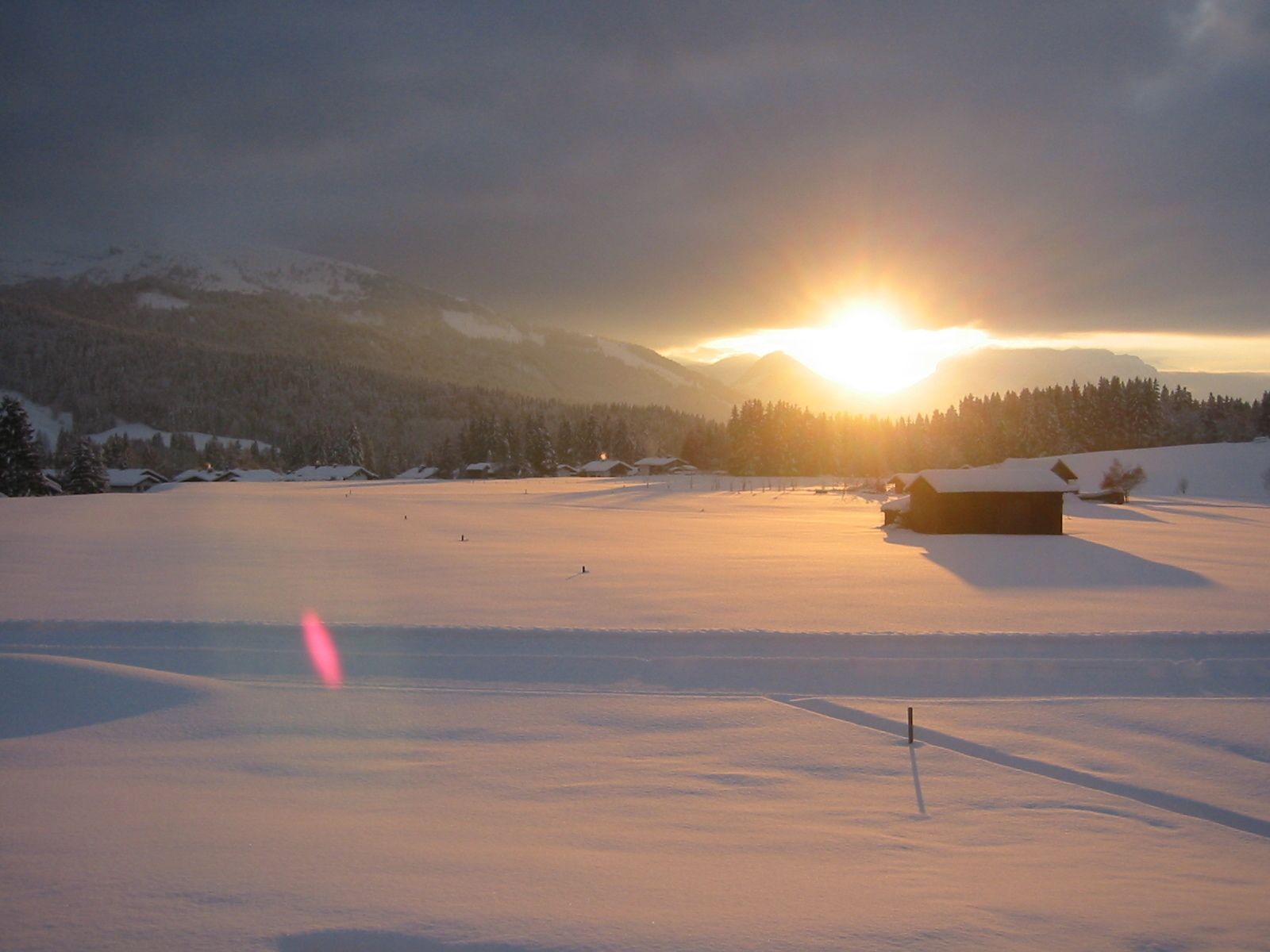 A snow-covered landscape with a wooden cabin and a clear sky.