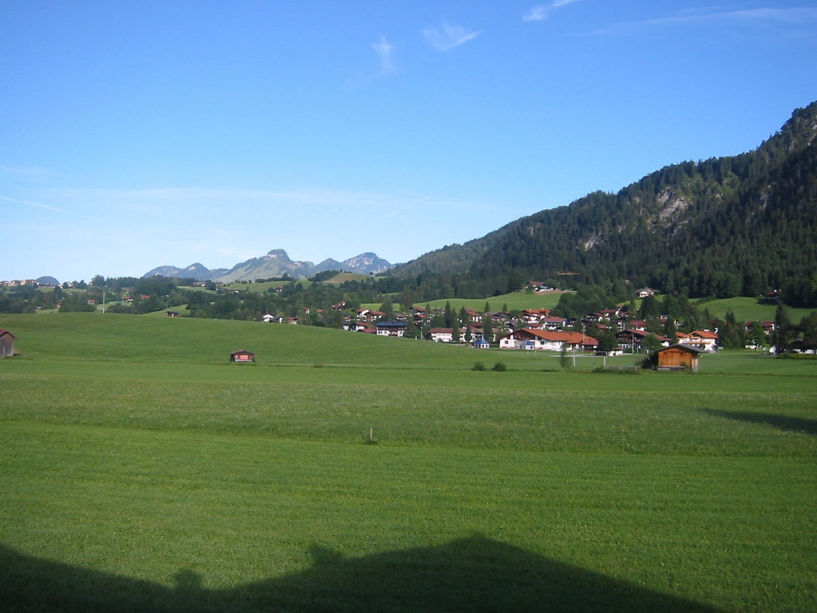 Un paysage rural avec un village niché au milieu de champs verdoyants et de montagnes.