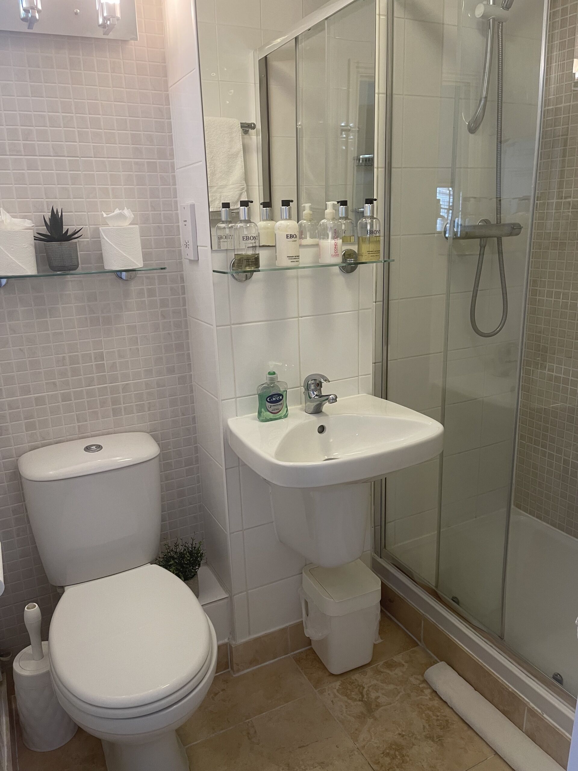 A modern bathroom with a toilet, sink, and glass shower enclosure.