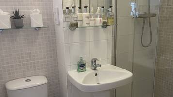 A modern bathroom with a toilet, sink, and glass shower enclosure.