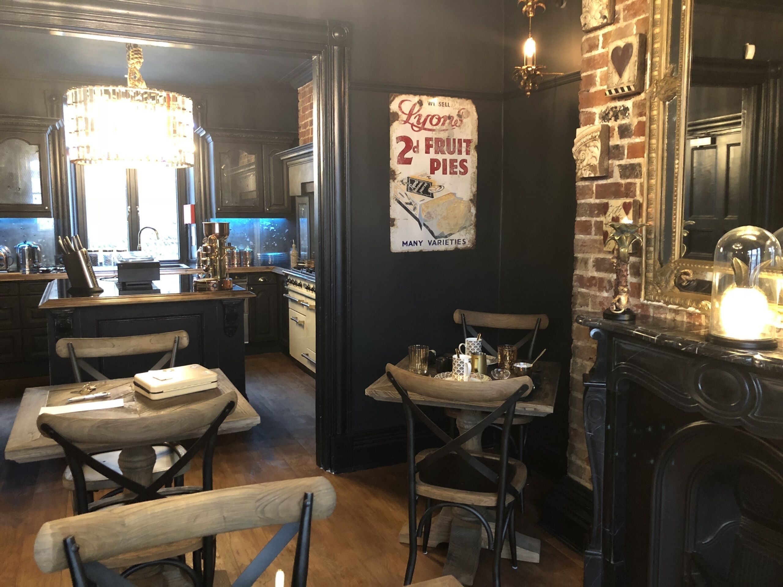 A cozy restaurant interior with a brick wall, a chandelier, and a poster advertising fruit pies.