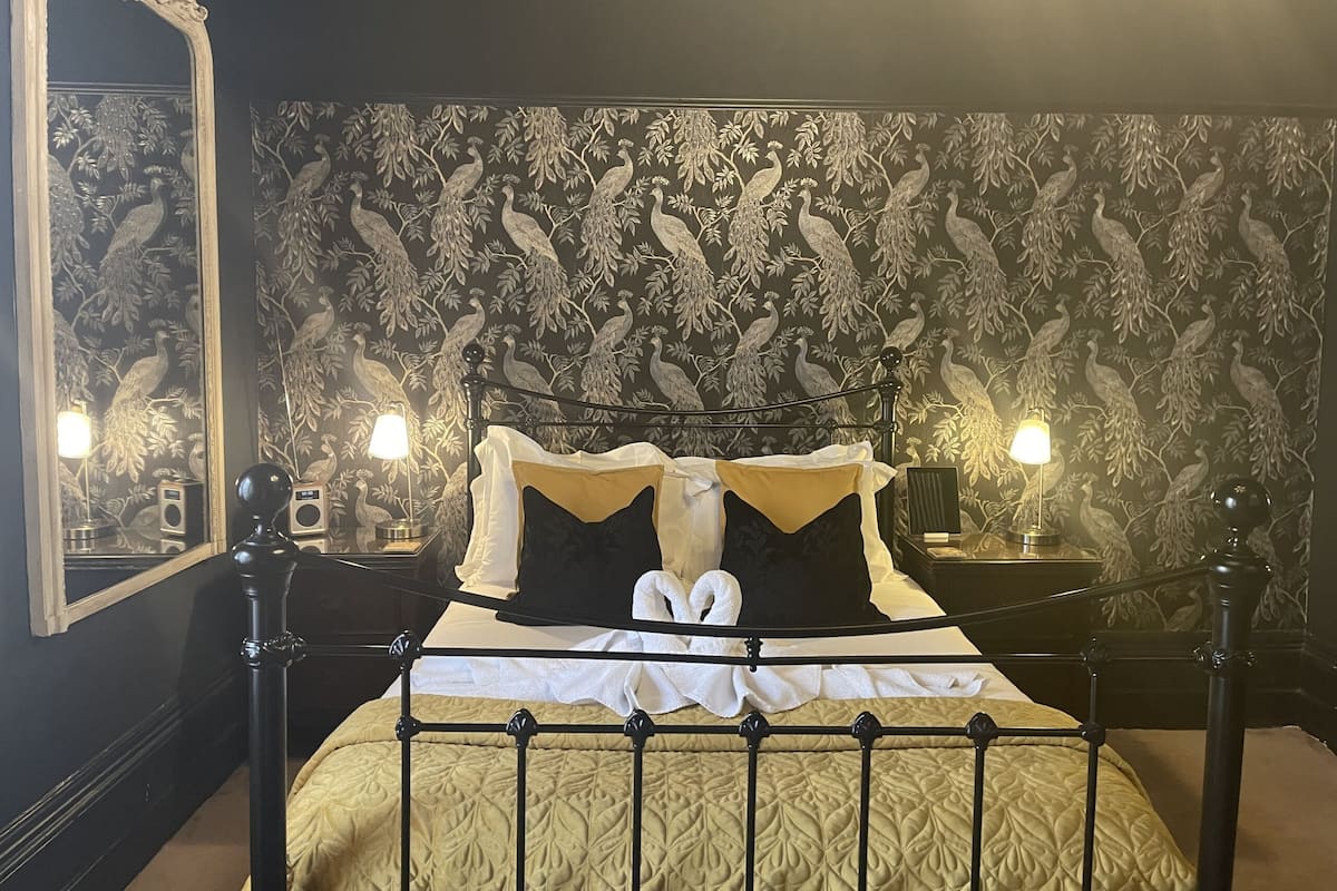 A bed with a metal frame, a quilted gold bedspread, and two bedside lamps.