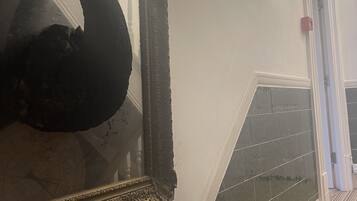 Una escultura de cisne en un espejo, una escalera con baldosas oscuras y una puerta con un botón de emergencia rojo.