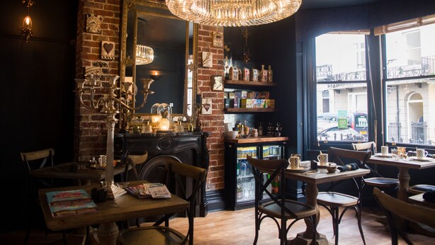 Un café acogedor con paredes de ladrillo, muebles de madera y una lámpara de araña grande.