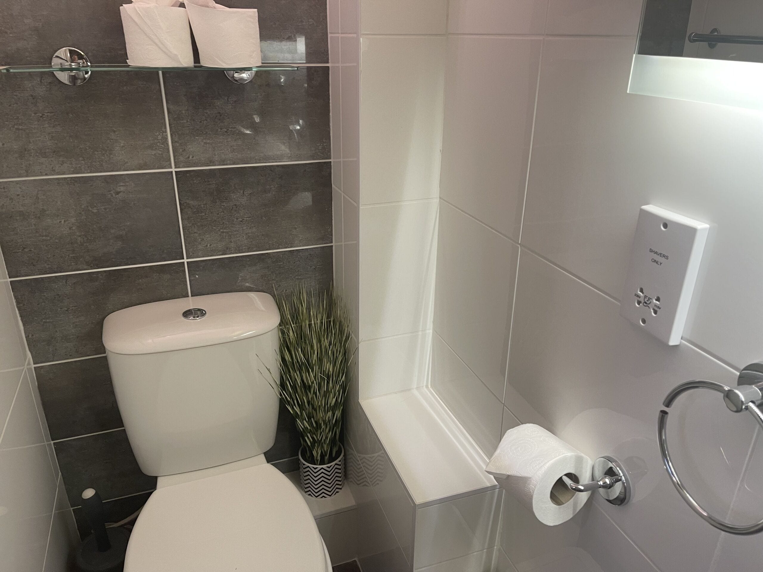 A modern bathroom with a toilet, a glass shower enclosure, and a toilet paper holder.