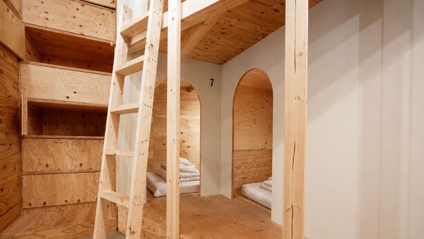 Un dormitorio tipo loft con escalera, estanterías empotradas y una cama litera.