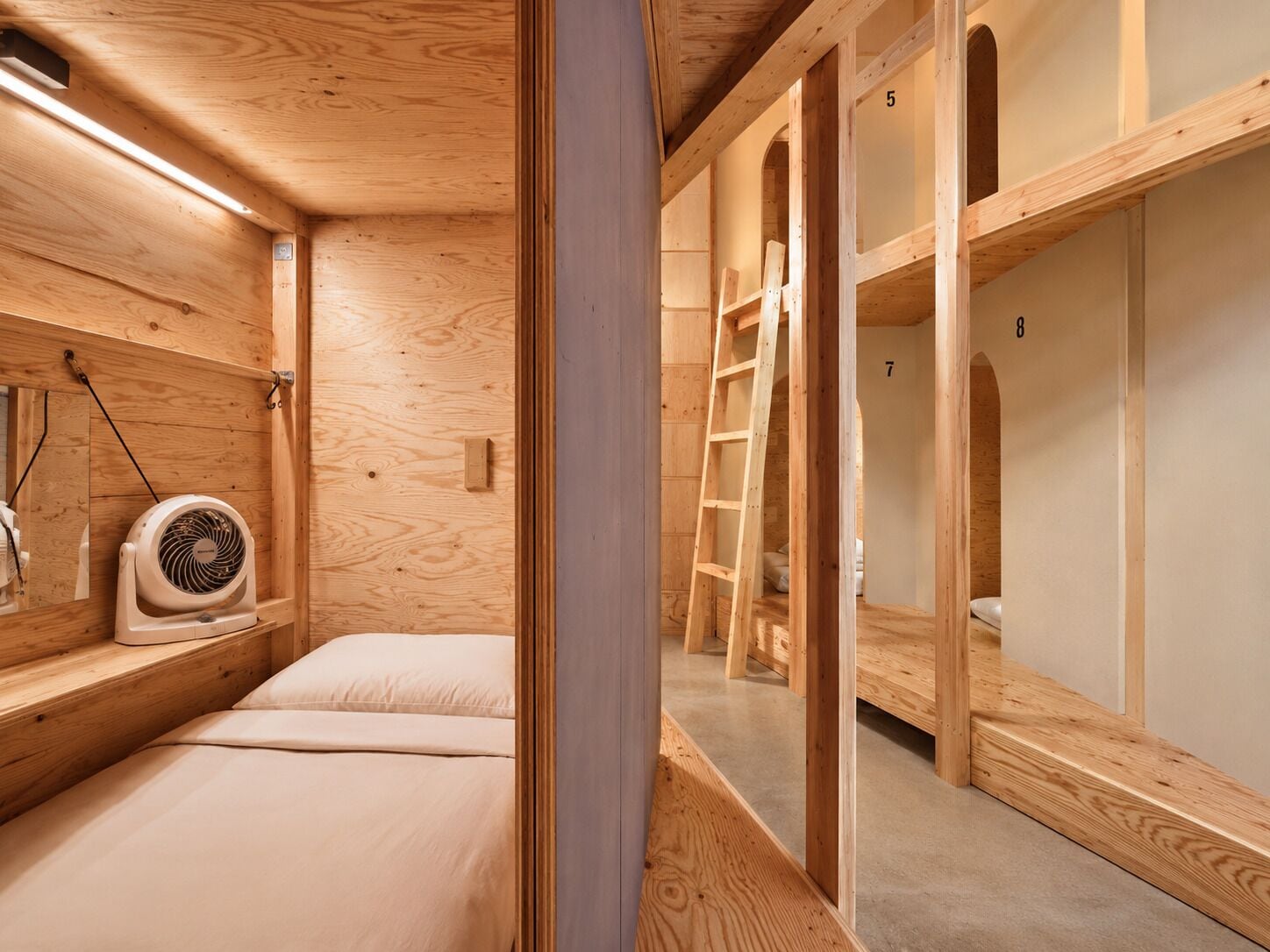 A wooden interior with bunk beds, a fan, and a ladder.