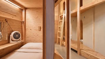 A wooden interior with bunk beds, a fan, and a ladder.
