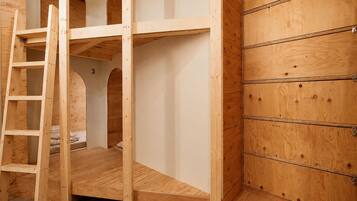 A bunk bed with a ladder, a wooden wardrobe, and a number '3' on the wall.