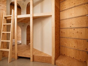 Ein Stockbett mit einer Leiter, ein Holzschrank und die Zahl 3 an der Wand.
