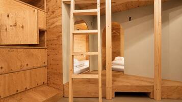 Quarto com beliche, escada de madeira, um pequeno guarda-roupa e o número 8 na parede.