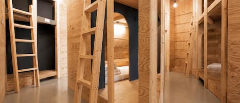 Interior de madera con literas, una escalera y una pared oscura.