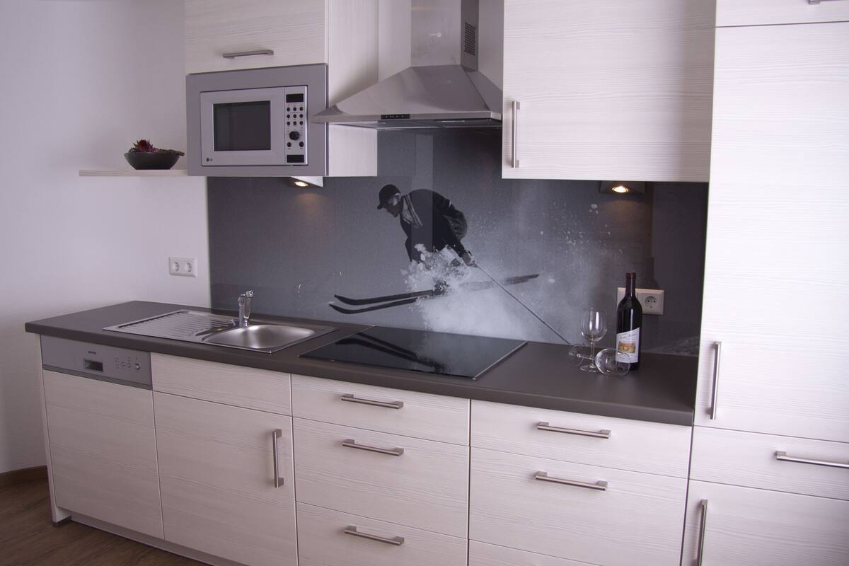 Cozinha moderna com micro-ondas, pia e garrafa de vinho.