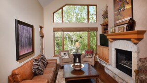 A cozy living room with a leather sofa, a wooden coffee table, and a fireplace.