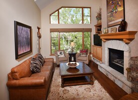 A cozy living room with a leather sofa, a wooden coffee table, and a fireplace.