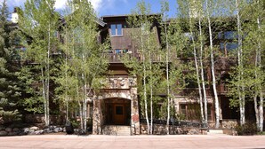 A multi-story lodge with a stone facade, large windows, and a wooden entrance.
