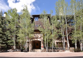 A multi-story lodge with a stone facade, large windows, and a wooden entrance.