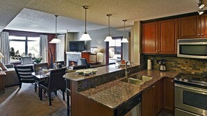 A modern kitchen with granite countertops, stainless steel appliances, and wooden cabinets. - Luxury Suites At The Blackstone Mountain Lodge 1 Bedroom Condo (Canmore)