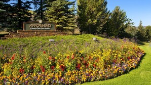 Señal del Arrowhead Country Club of the Rockies rodeado por un jardín de flores vibrante.