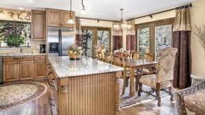 A spacious kitchen with wooden cabinets, a large island, and a dining area with a table and chairs. - Vail Point (Vail)