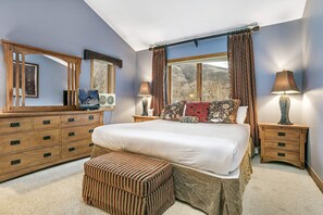 A bedroom with a large bed, wooden dresser, two bedside tables, a window with curtains, and a mirror. - Vail Point (Vail)