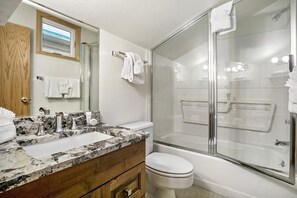 A bathroom with a double sink, a toilet, a glass shower enclosure, and a mirror with a towel rack. - Vail Point (Vail)