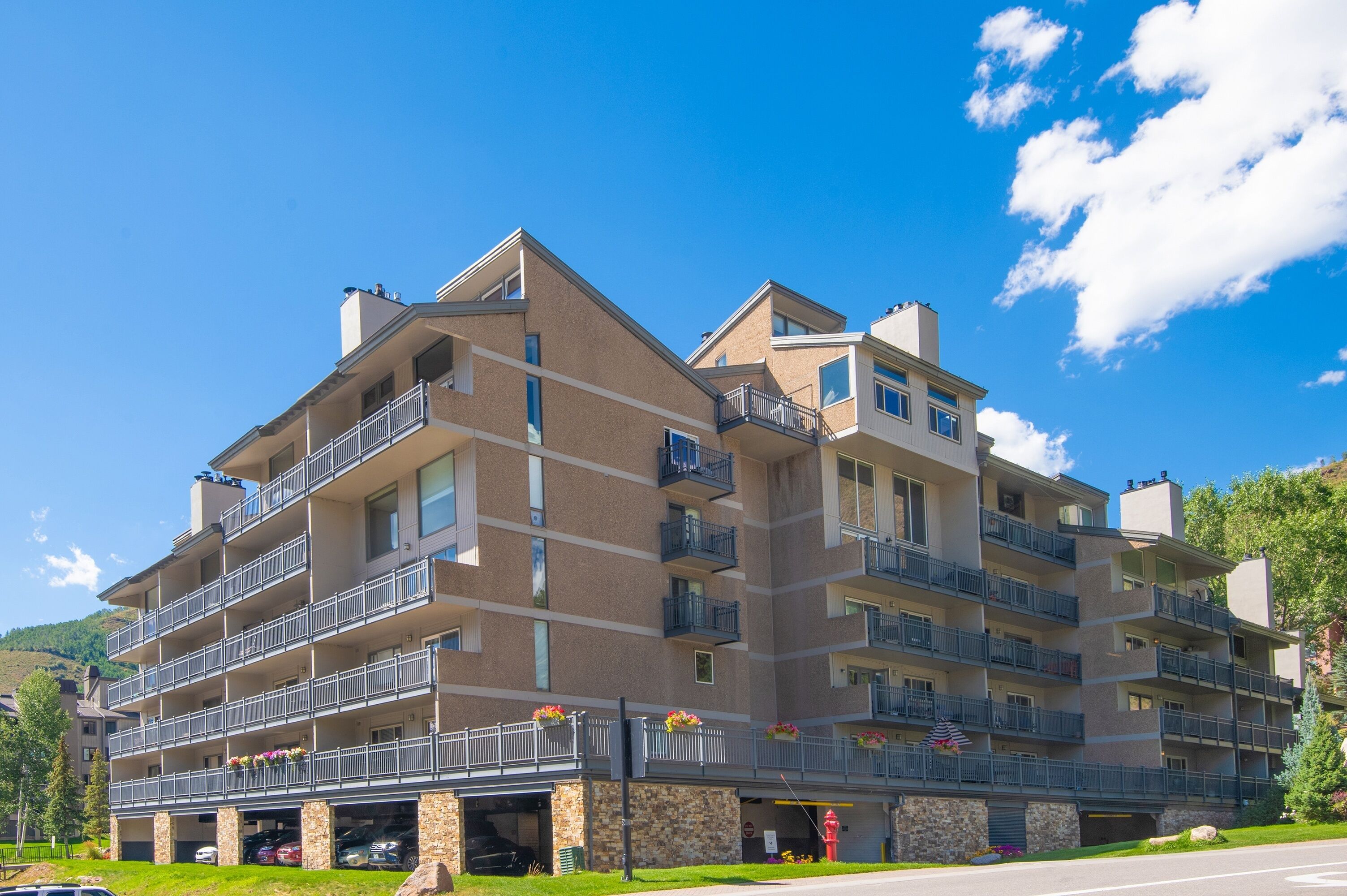 A multi-story hotel with balconies, a parking garage, and a view of the surrounding landscape.