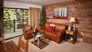 A cozy living room with a leather sofa, a wooden coffee table, and a dining table.