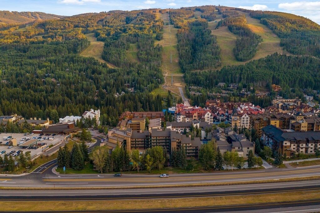 Une ville où se côtoient des bâtiments résidentiels et commerciaux, une rue principale et un paysage vallonné en arrière-plan.