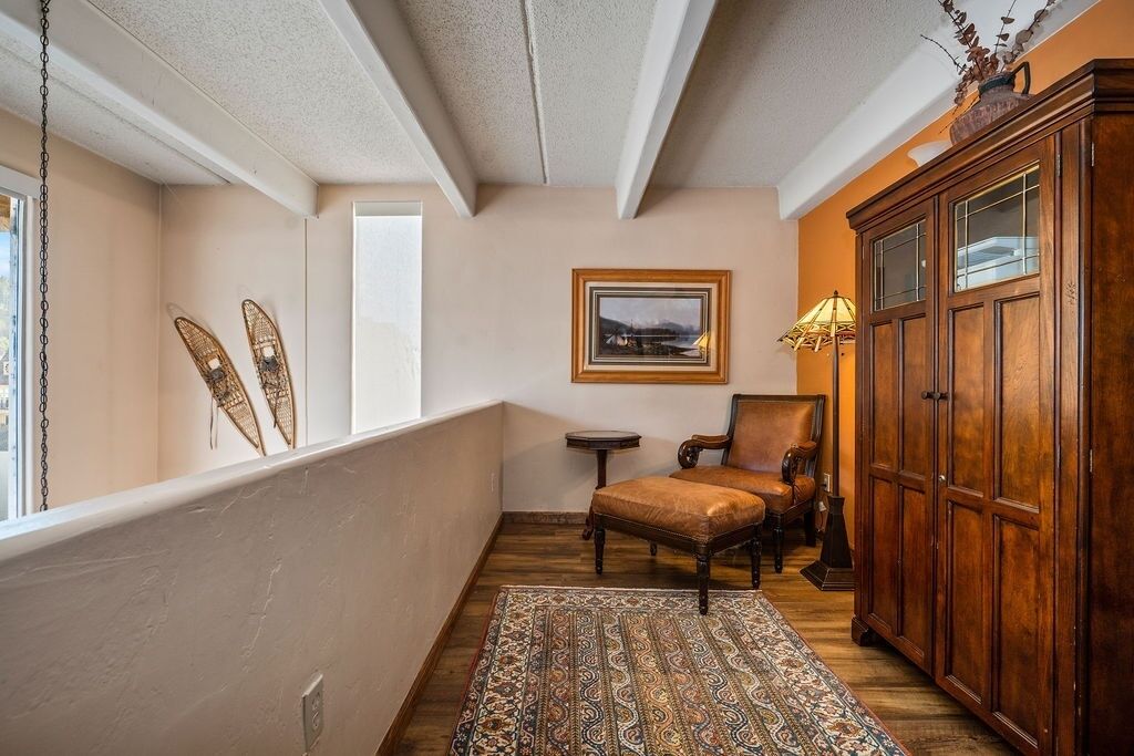 A cozy room with a wooden floor, a patterned rug, a wooden cabinet, and a chair.