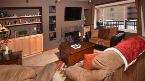 Una sala de estar acogedora con chimenea, un sofá, una mesa de centro y una estantería.