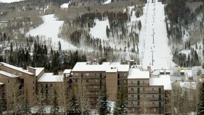 Un complejo de esquí con varios edificios, un telesilla y una montaña nevada al fondo.
