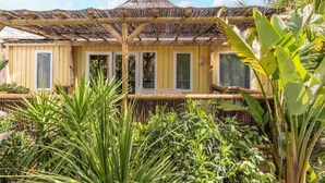 A thatched-roof structure with a yellow facade, surrounded by lush tropical vegetation. - La Toison d'Or Resort & Spa (Ramatuelle)