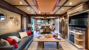 A cozy living area with a sofa, a wooden coffee table, and a TV on the right. - La Toison d'Or Resort & Spa (Ramatuelle)