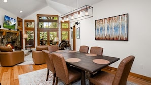 Un coin repas avec une table en bois foncé, des chaises en cuir marron et un grand tableau accroché au mur.