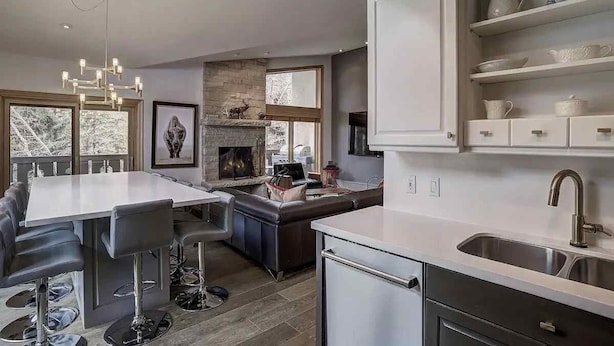 A modern kitchen with a dining area, built-in cabinets, and a fireplace. - Riva Ridge 630 4 Bedroom Condo by RedAwning (Vail)