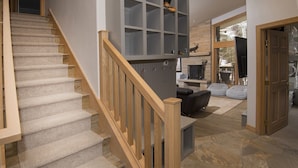 A staircase with wooden railings leading to a living area with a stone floor, a fireplace, and a seating area with a sofa and bean bag. - Riva Ridge 630 4 Bedroom Condo by RedAwning (Vail)