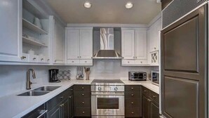 A modern kitchen with white cabinets, stainless steel appliances, and a built-in oven. - Riva Ridge 630 4 Bedroom Condo by RedAwning (Vail)