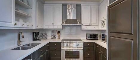 A modern kitchen with white cabinets, stainless steel appliances, and a built-in oven.