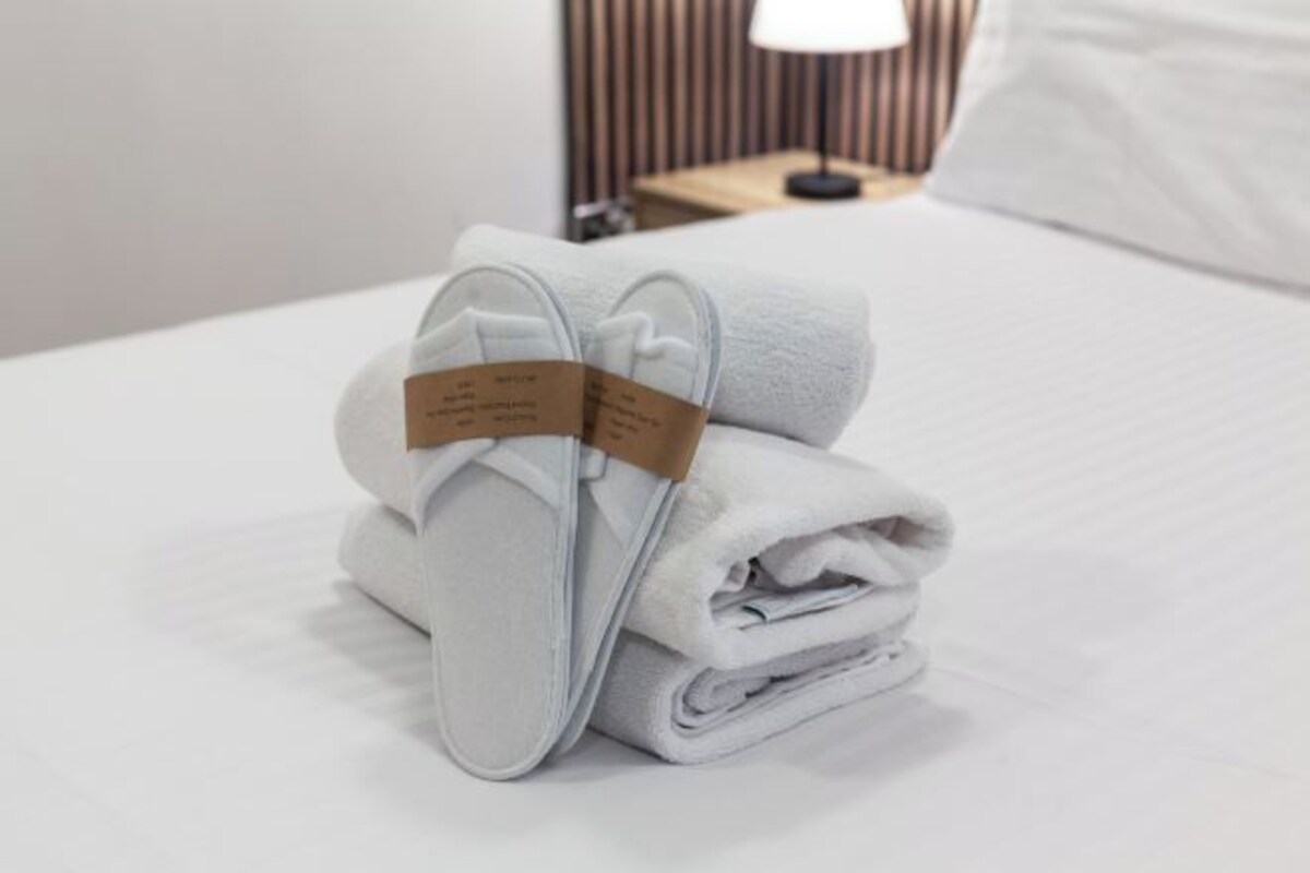A neatly folded white towel with a tag on a bed.