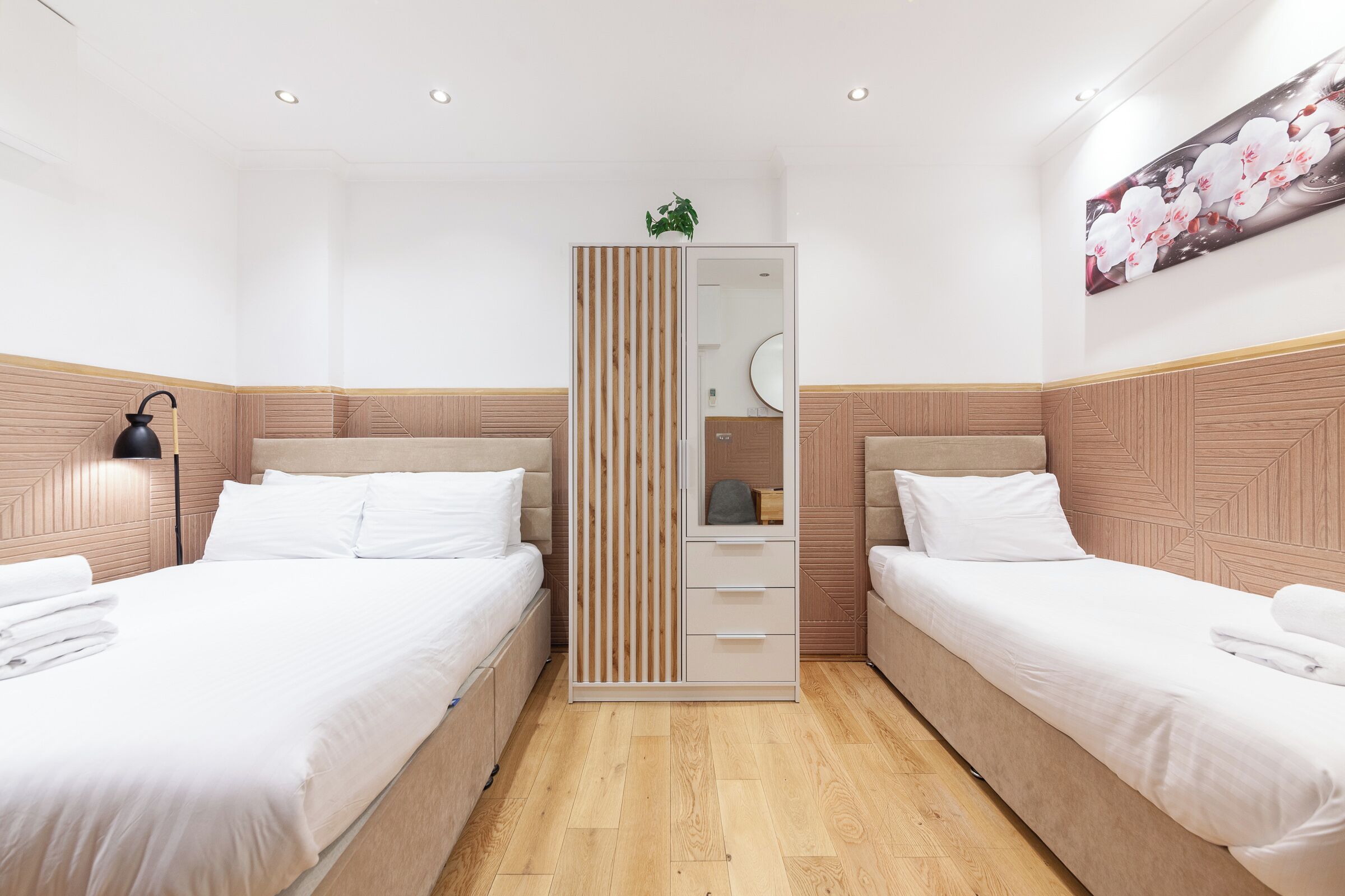 Ein Hotelzimmer mit zwei Betten, einem Schrank, einem Spiegel und einem Wandbild.