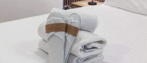 A neatly folded white towel with a tag on a bed.