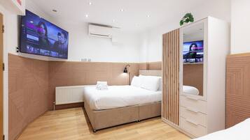 Un dormitorio moderno con una cama grande, un armario, un televisor montado en la pared y una lámpara en el techo.