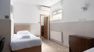 A hotel room with a bed, a wooden cabinet, a radiator, and a window.