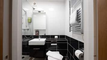 A modern bathroom with a white sink, black tiled walls, a toilet, and a towel rack.