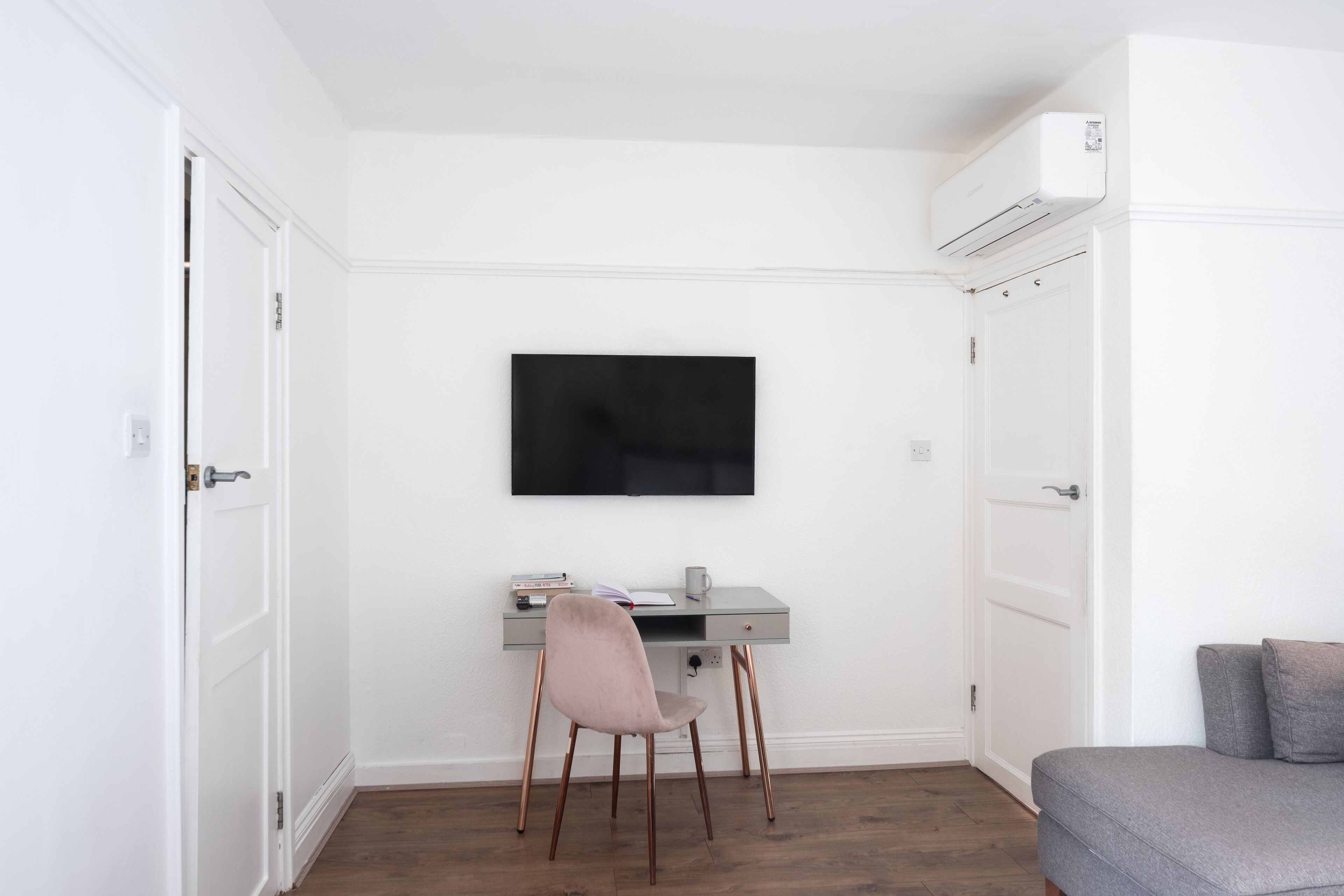 Una habitación con escritorio, silla y televisor montado en la pared.